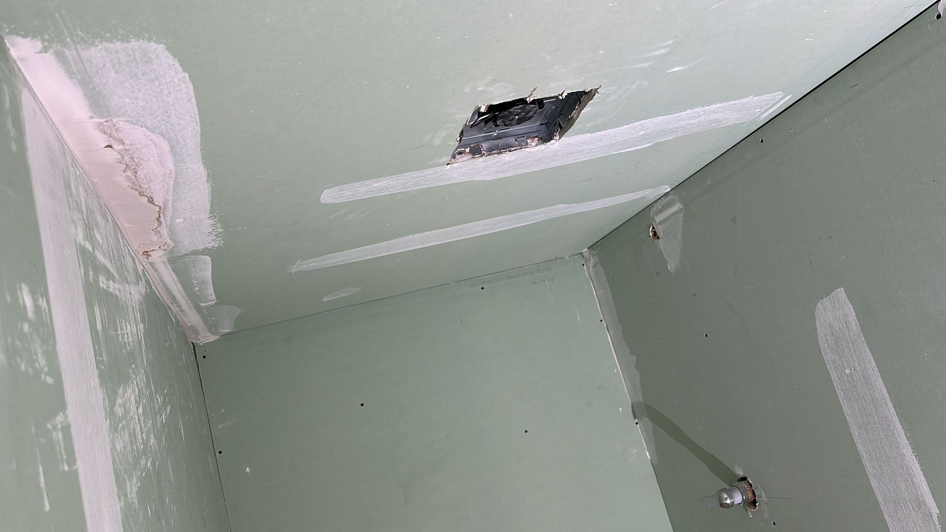 Drywall ceiling and walls, with patched sections and a rectangular hole.