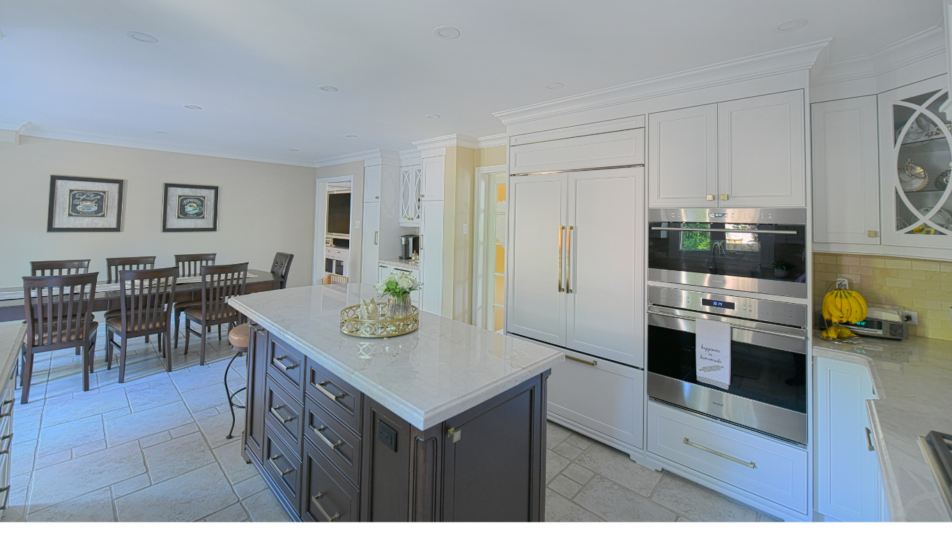 A modern kitchen with a large island, white cabinets, stainless steel appliances, and a dining area with a table and chairs.