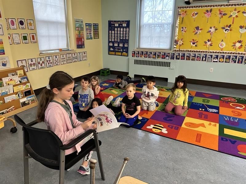 A group of children are sitting on the floor in a classroom.