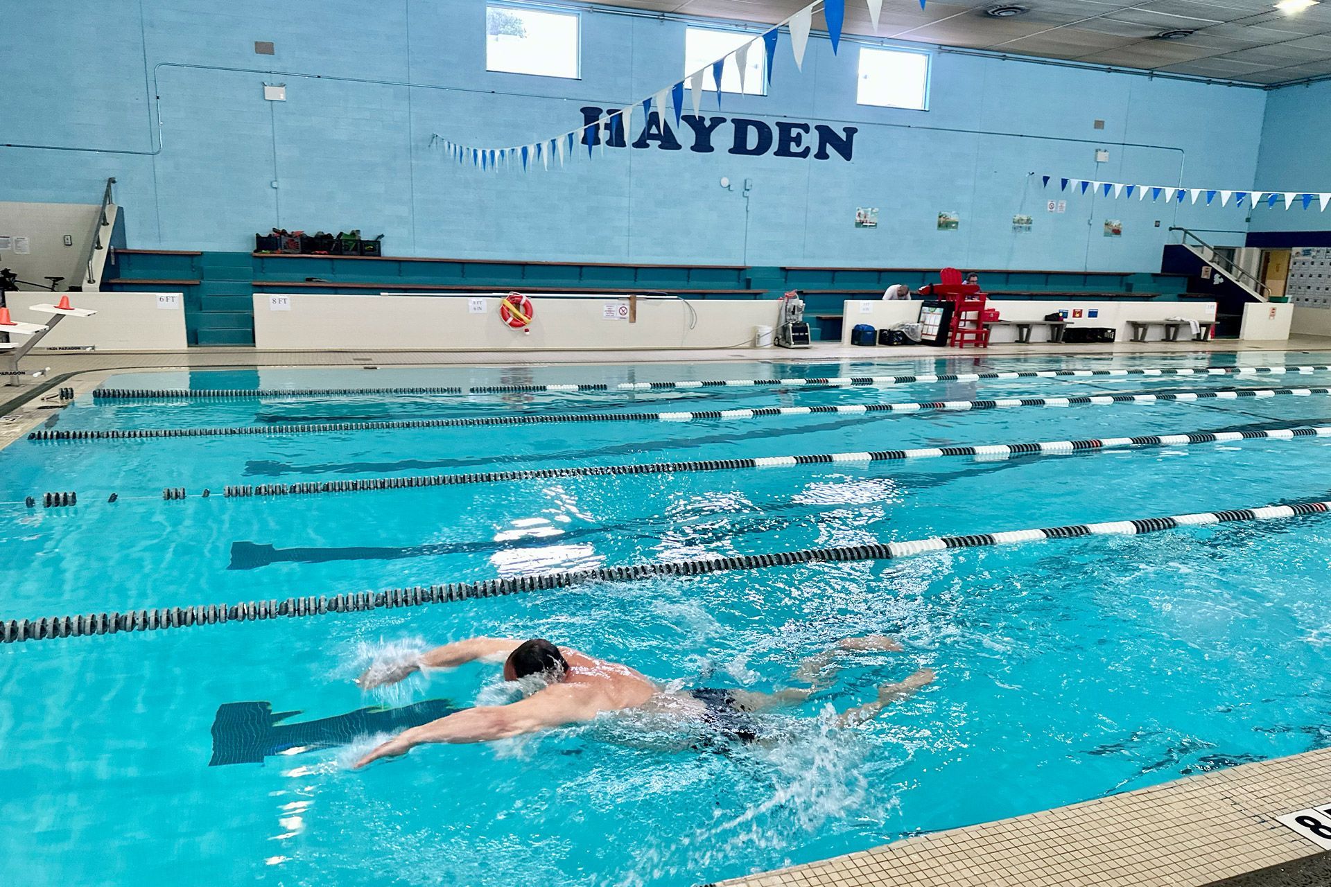 A man is swimming in a pool with the word hayden on the wall.