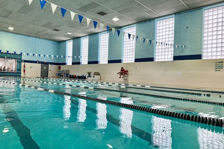 A large indoor swimming pool with flags hanging from the ceiling