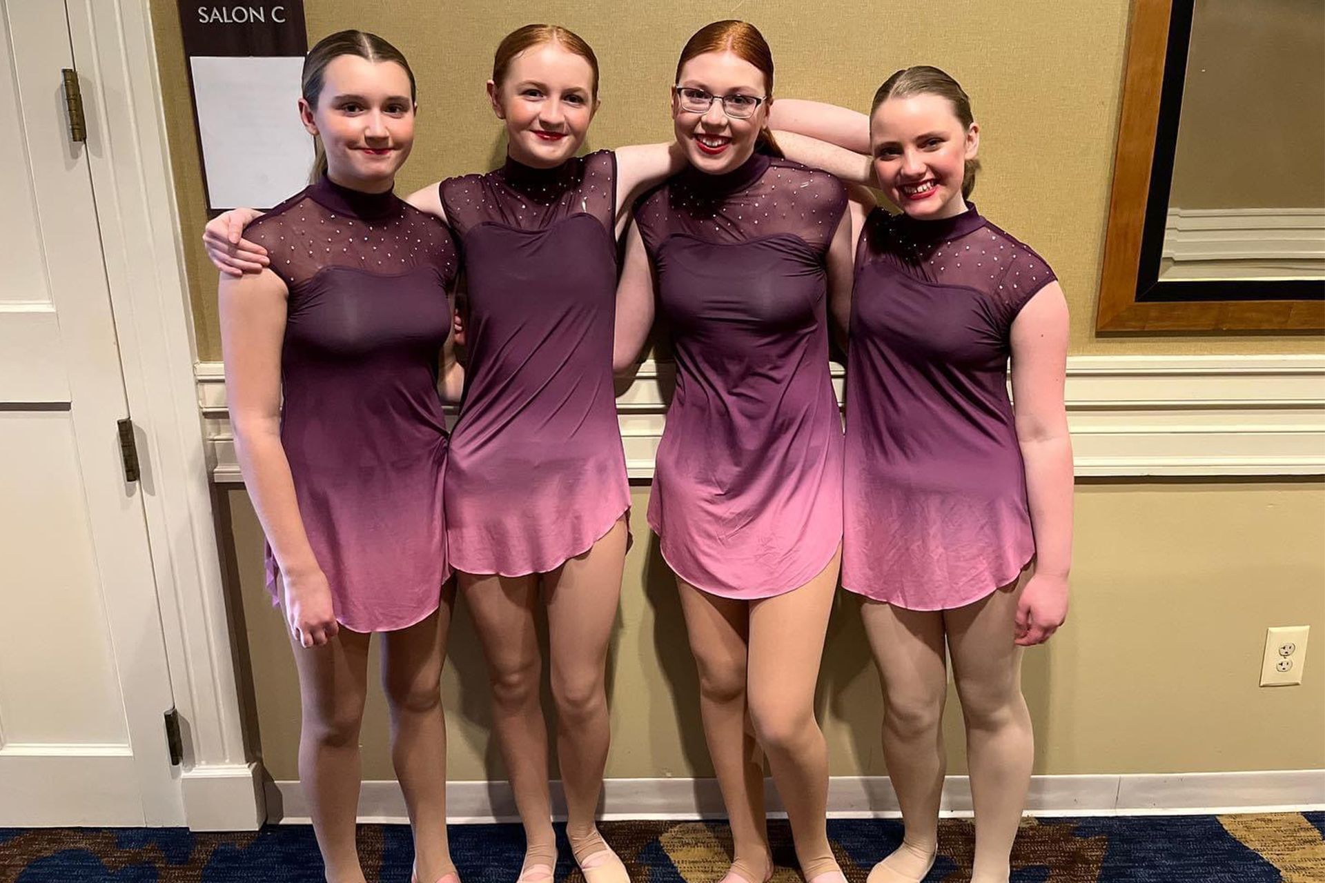 A group of young women in purple dresses are posing for a picture.