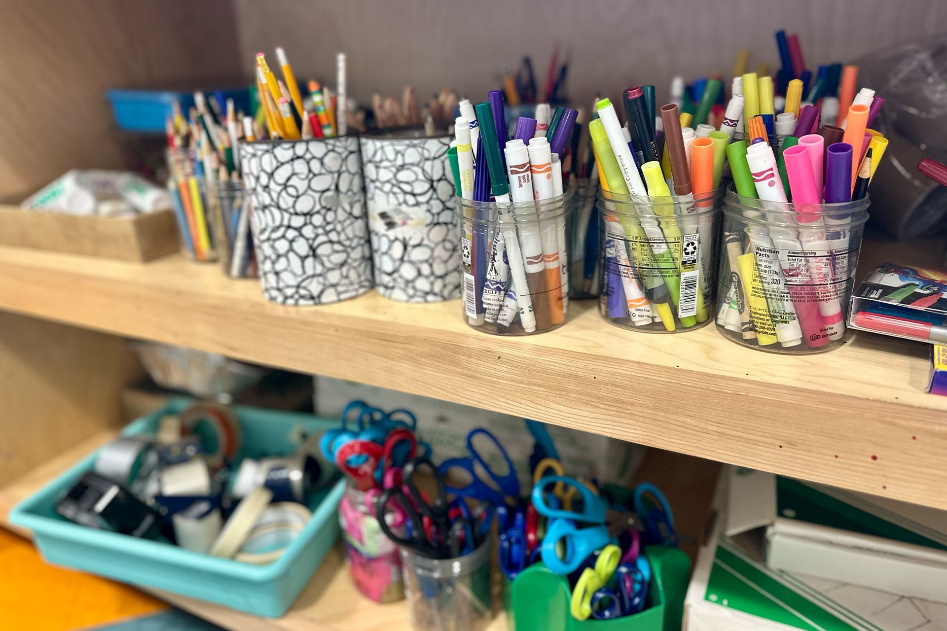 A shelf filled with lots of school supplies including scissors and markers.