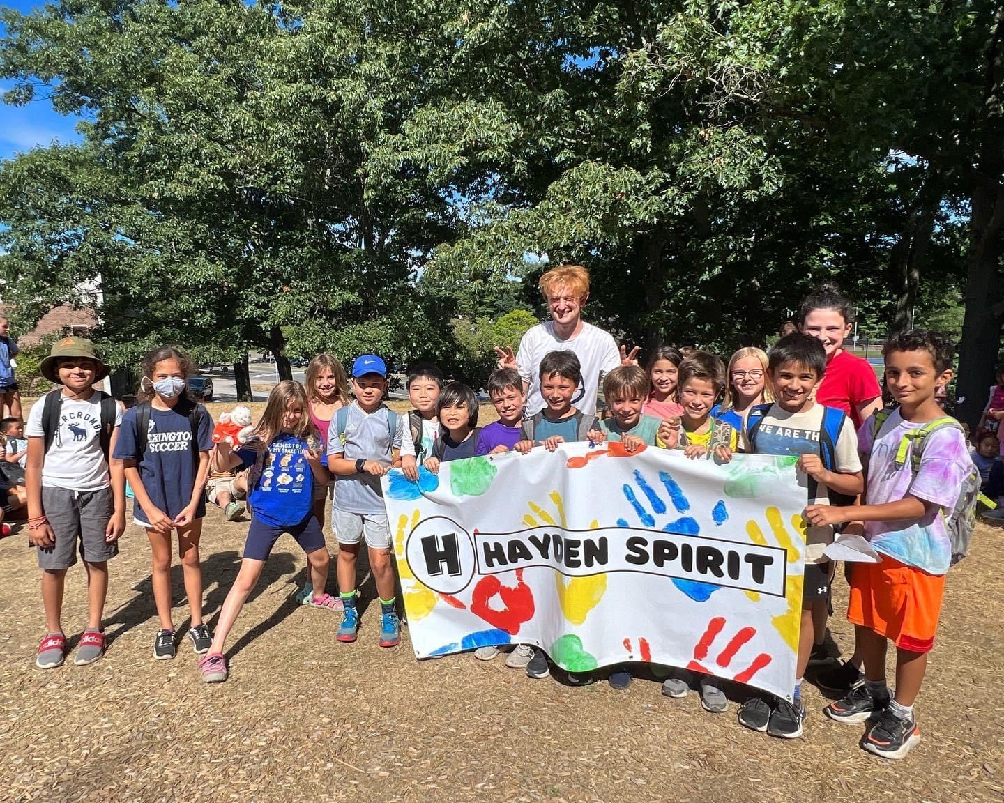 A group of children are holding a banner that says hayden spirit.