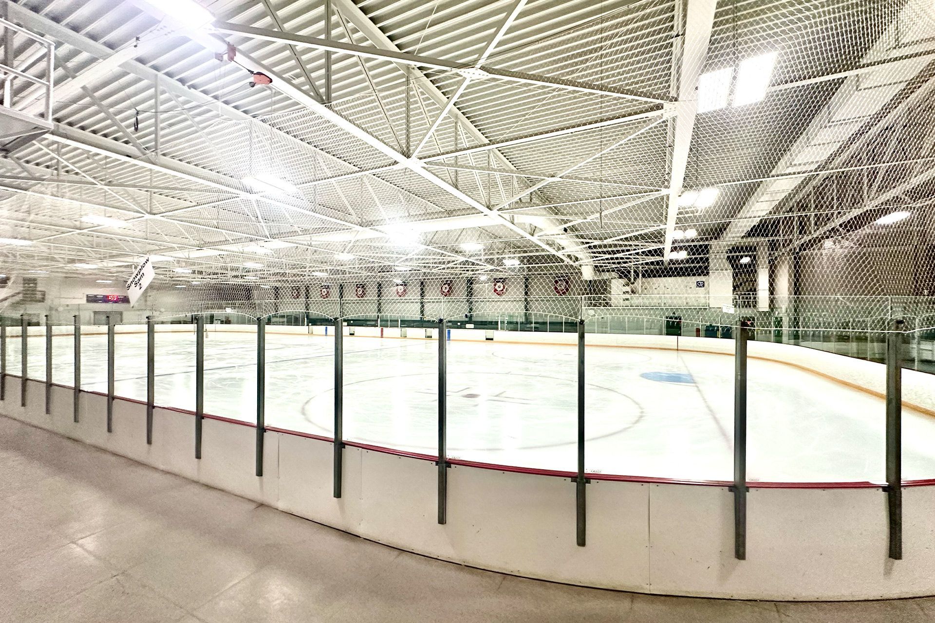 A large indoor ice rink with a fence around it.