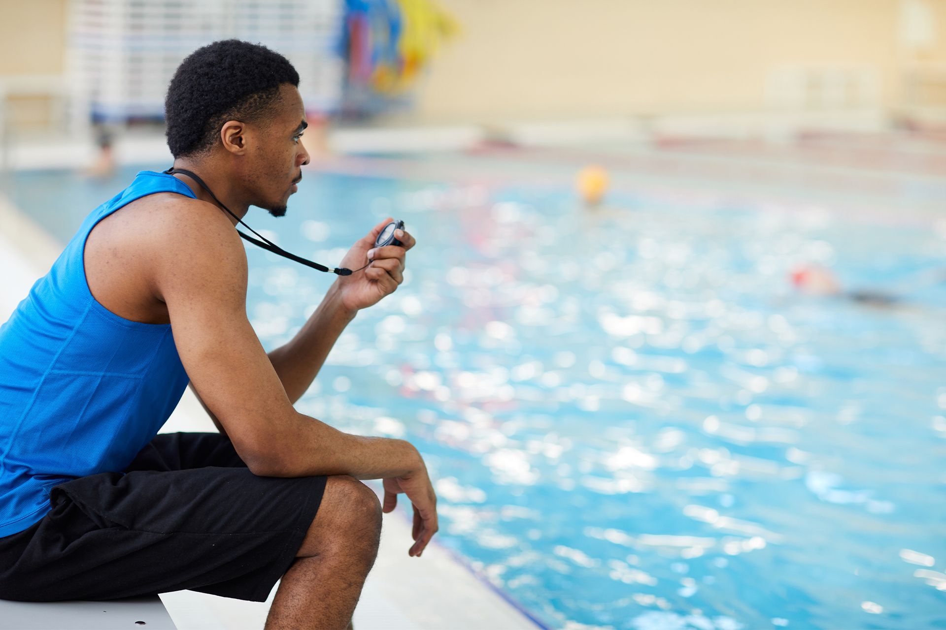 A man is sitting on the edge of a swimming pool.
