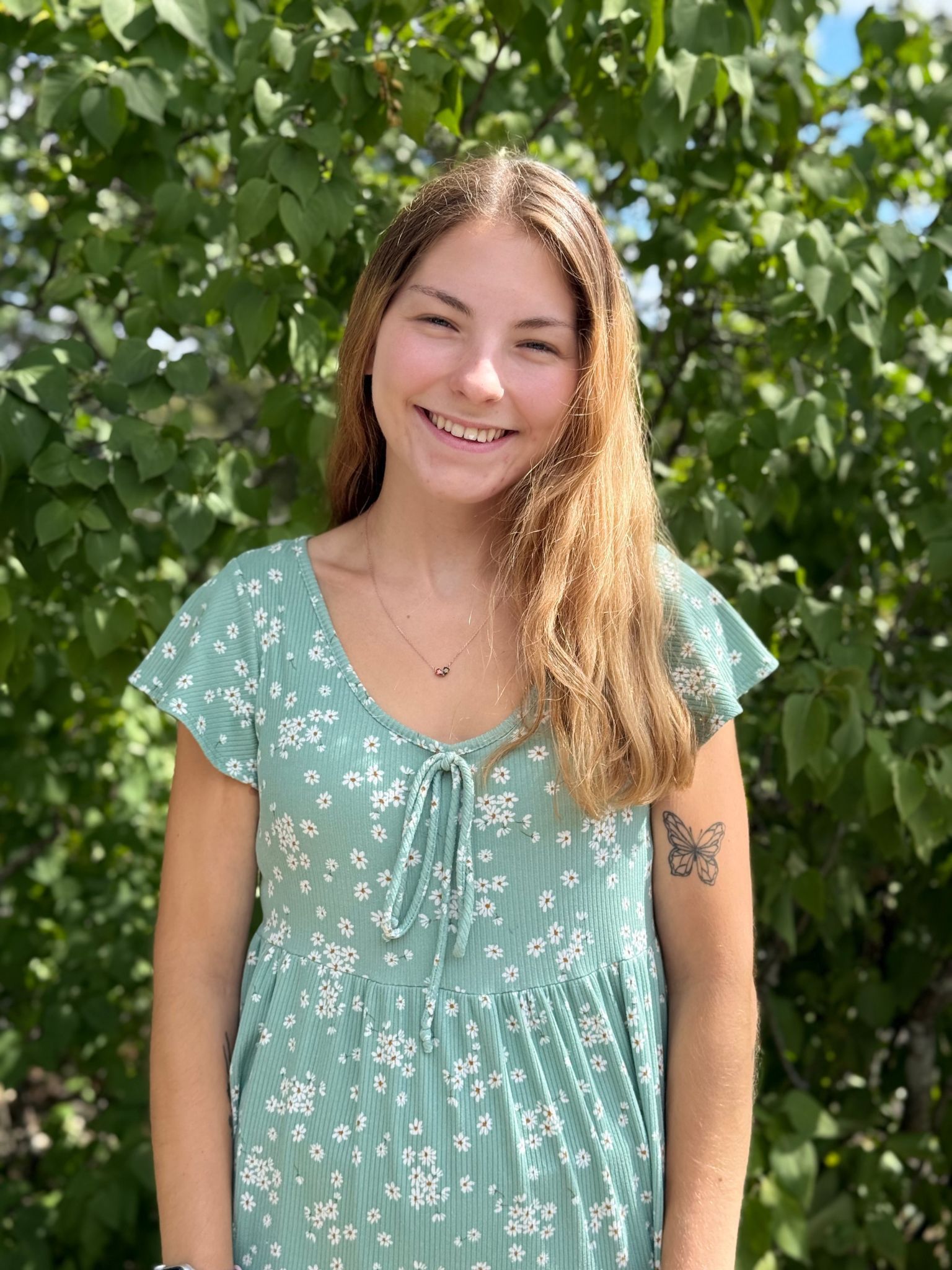 A young woman in a red polka dot top is smiling for the camera.