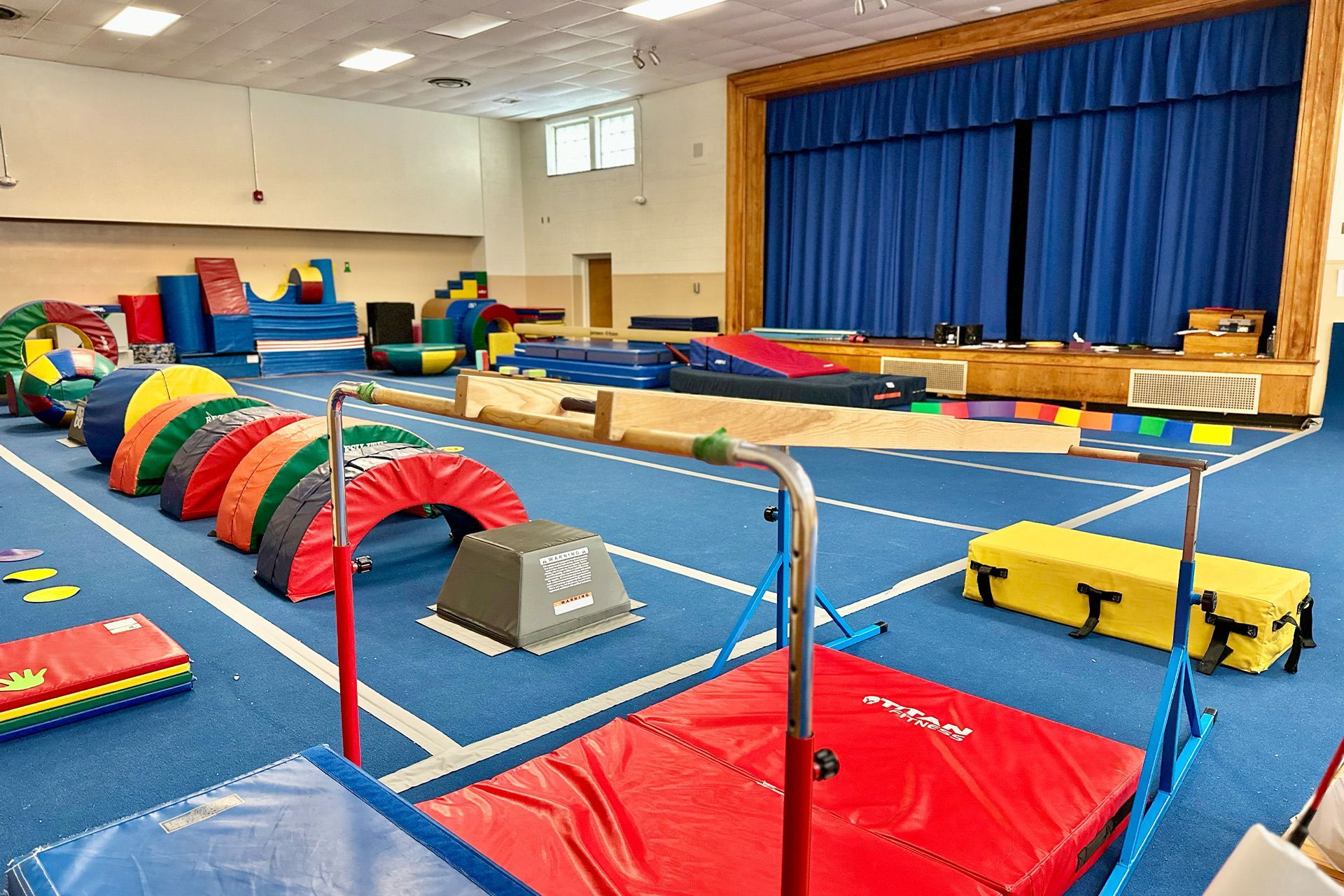 A gym filled with a variety of exercise equipment and a stage.