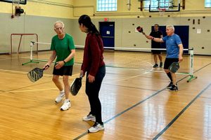 A group of people are playing a game of pickleball in a gym.