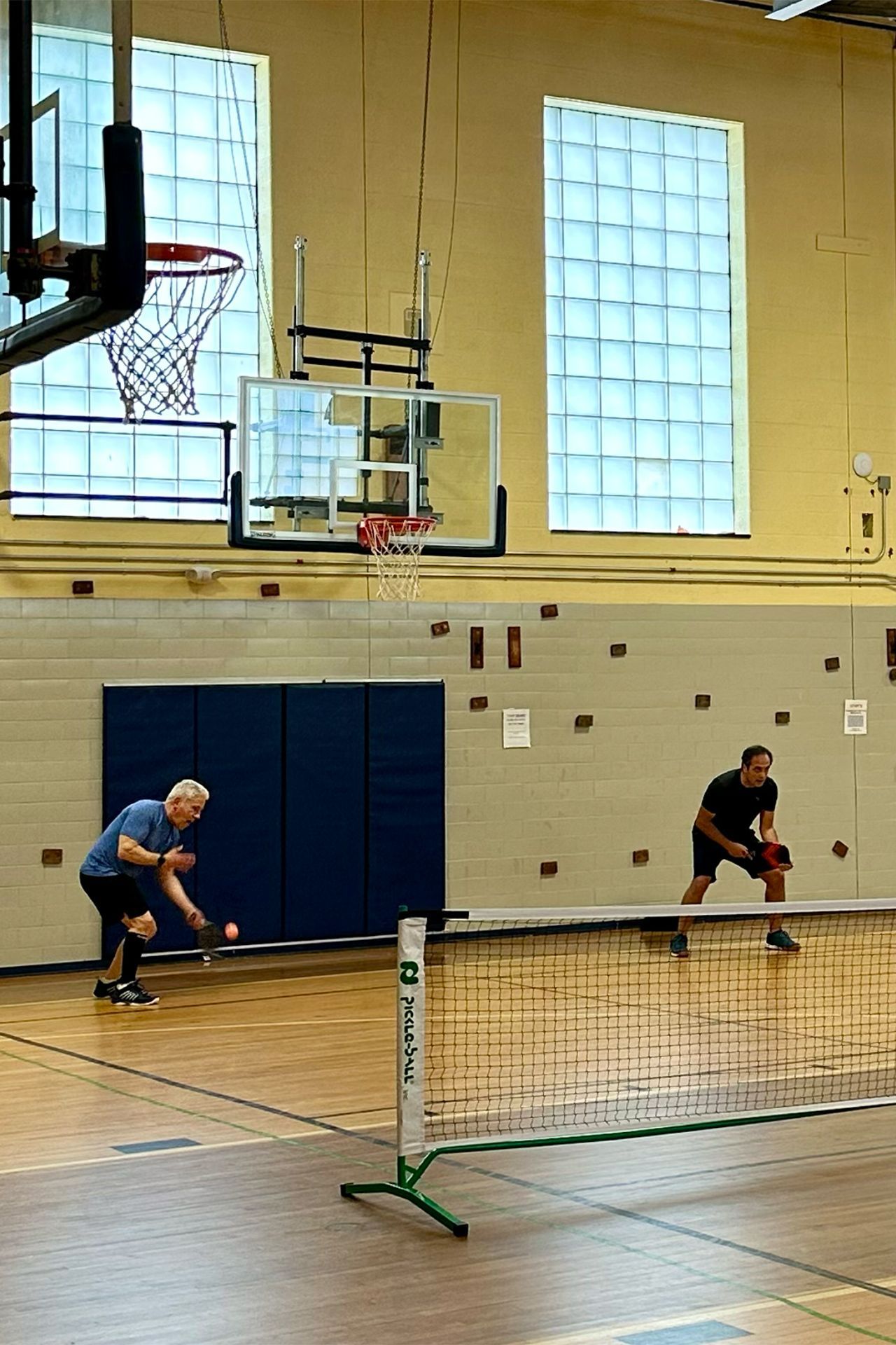 Two men are playing a game of tennis in a gym