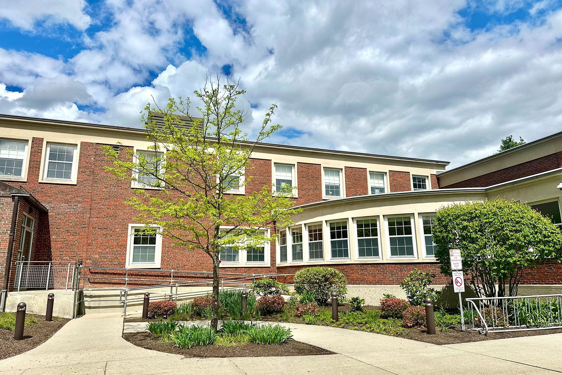A large brick building with a lot of windows and trees in front of it.