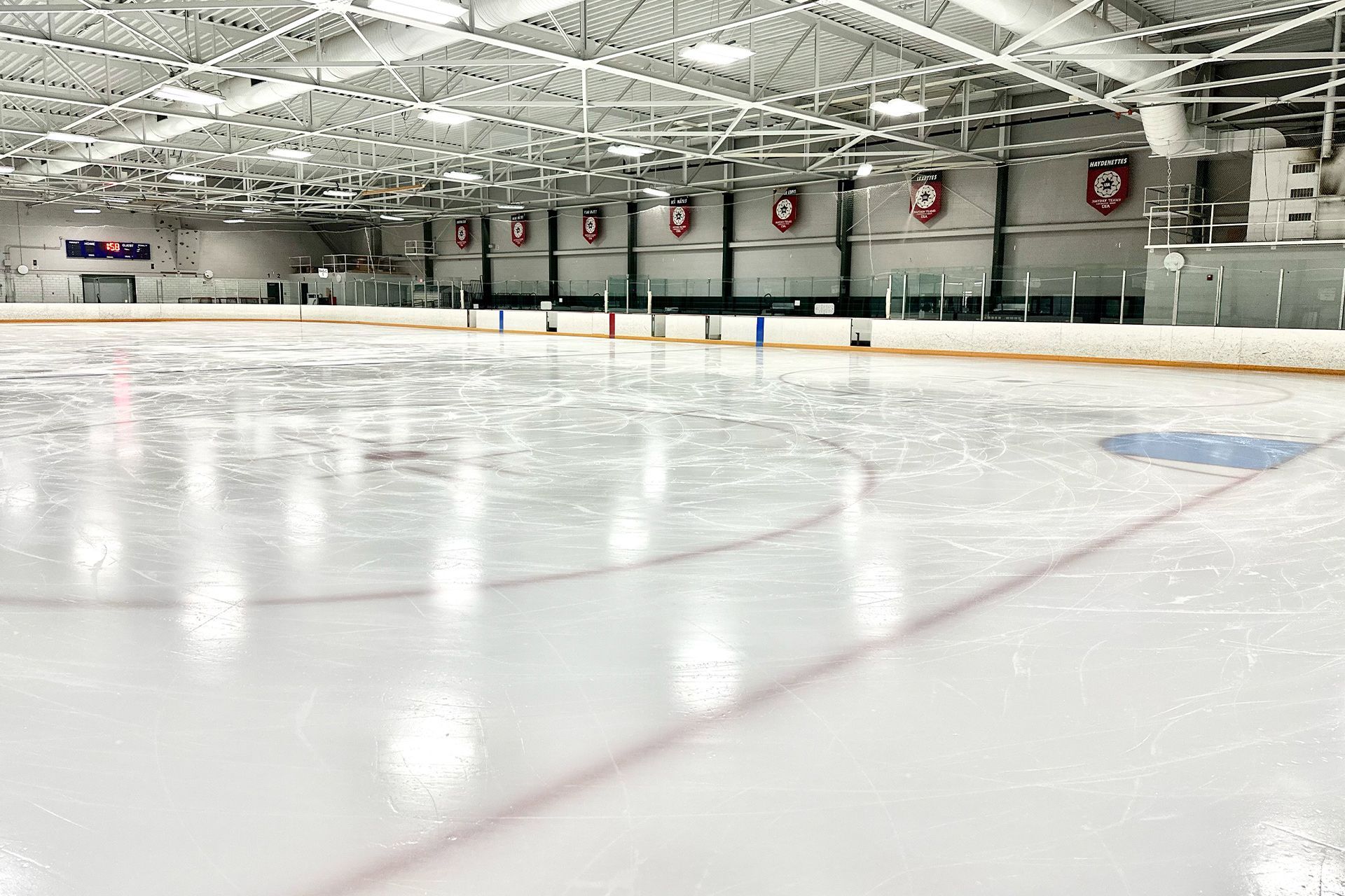 A large indoor ice rink with a lot of lights on it.