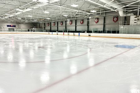 A large indoor ice rink with a lot of lights on it.