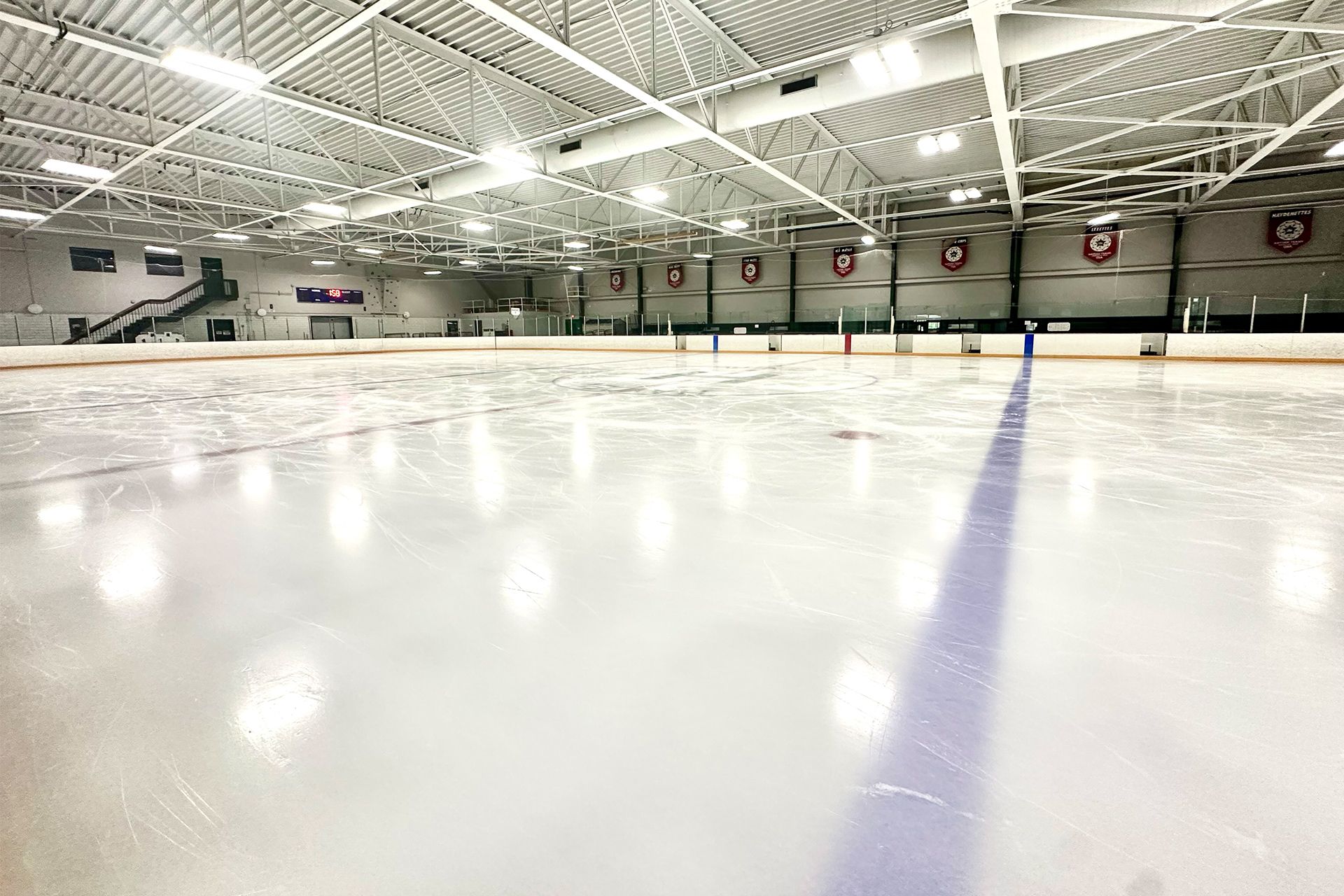 A large indoor ice rink with a fence around it.