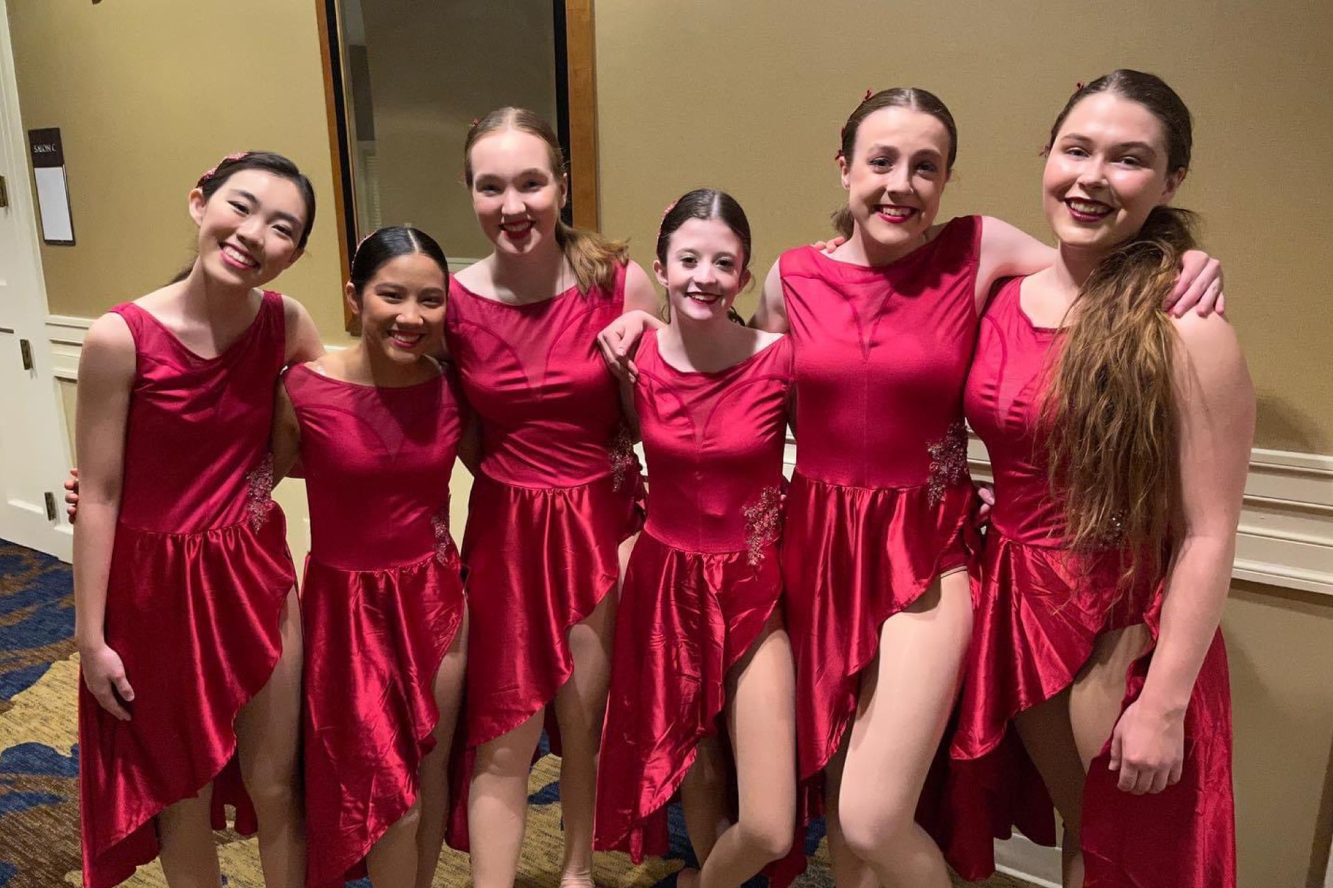 A group of young women in red dresses are posing for a picture.