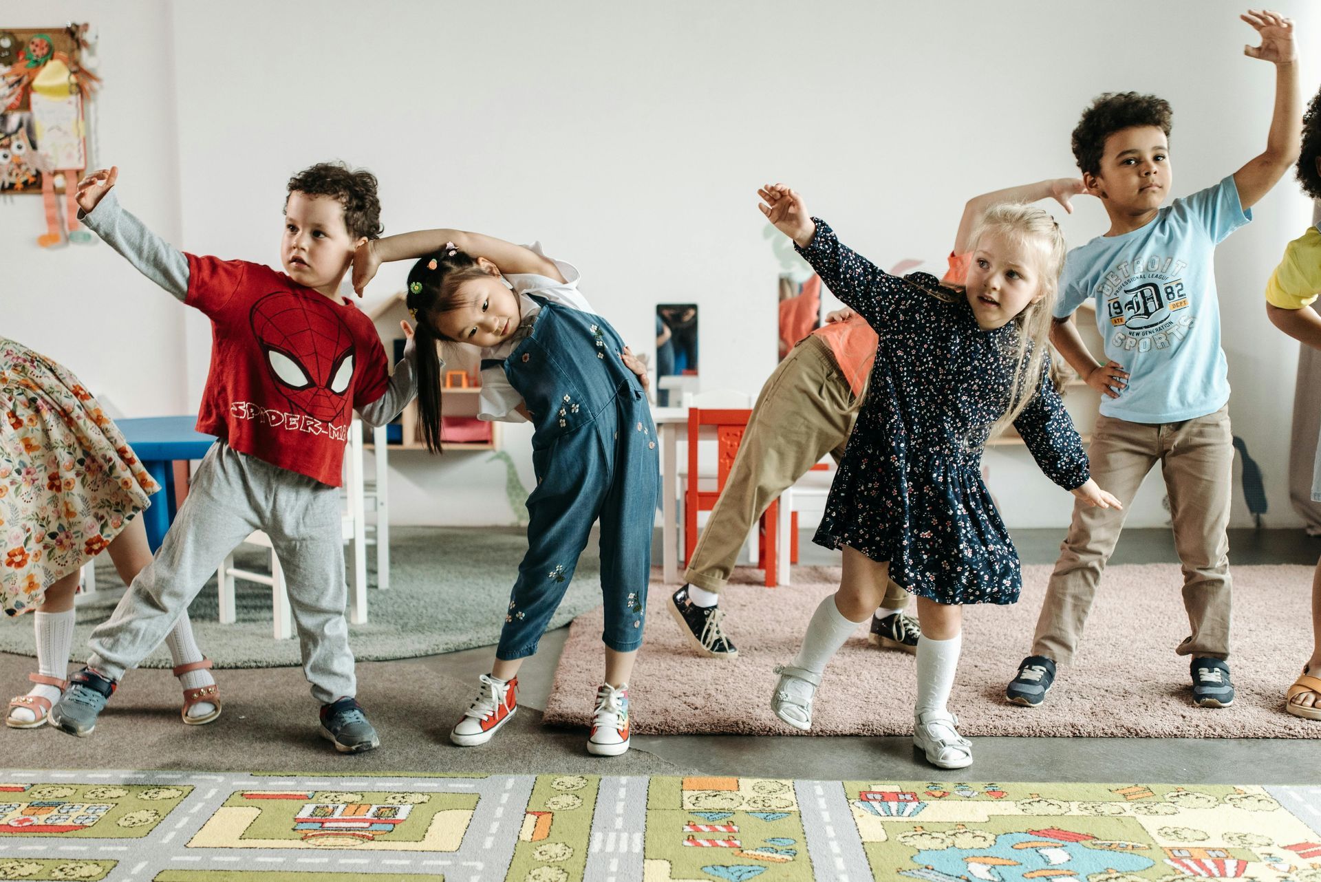 A group of children are dancing together in a classroom.