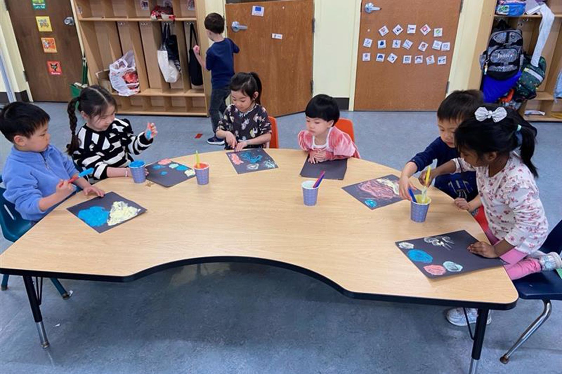 A group of children are sitting around a table in a classroom