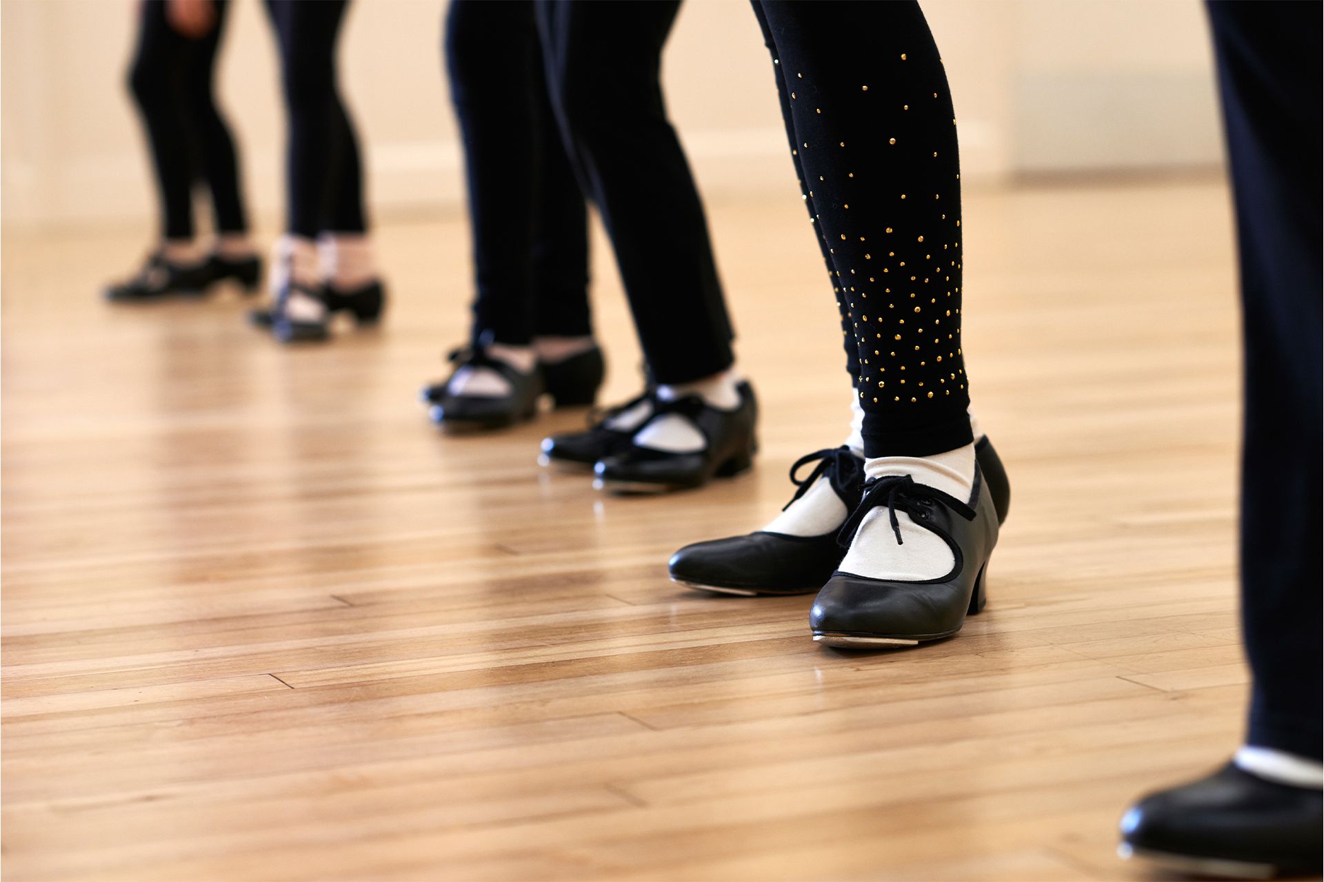 A group of people are dancing tap in a dance studio.