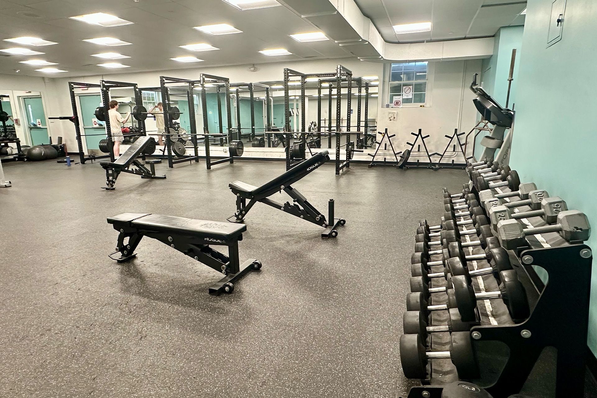 A large gym with a lot of dumbbells and benches.