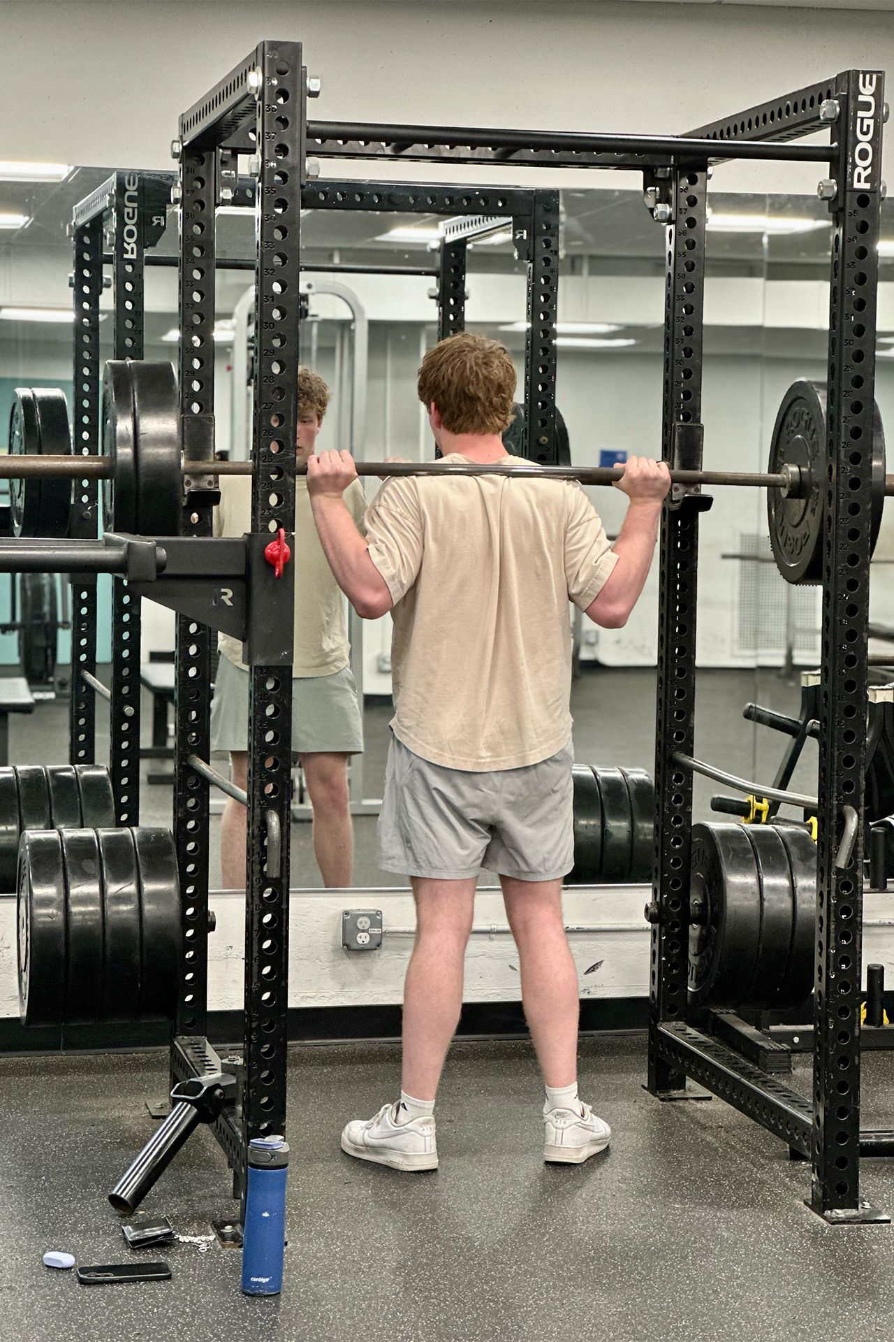 A man is squatting with a barbell in a gym.