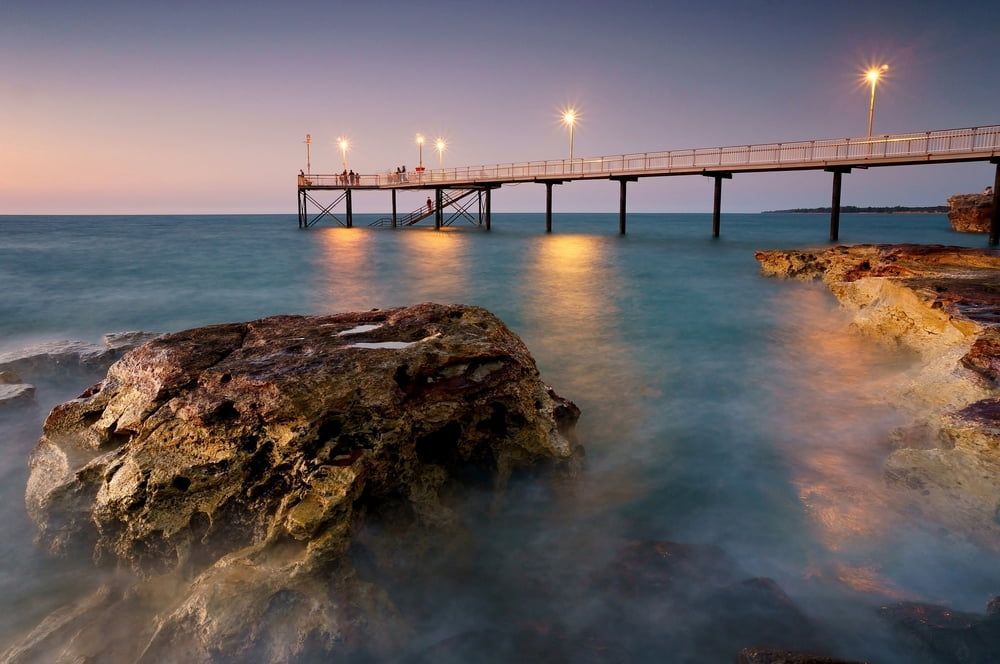 A Pier Overlooking a Body of Water With Rocks — Great Northern Airconditioning & Mechanical Services in Nightcliff, NT