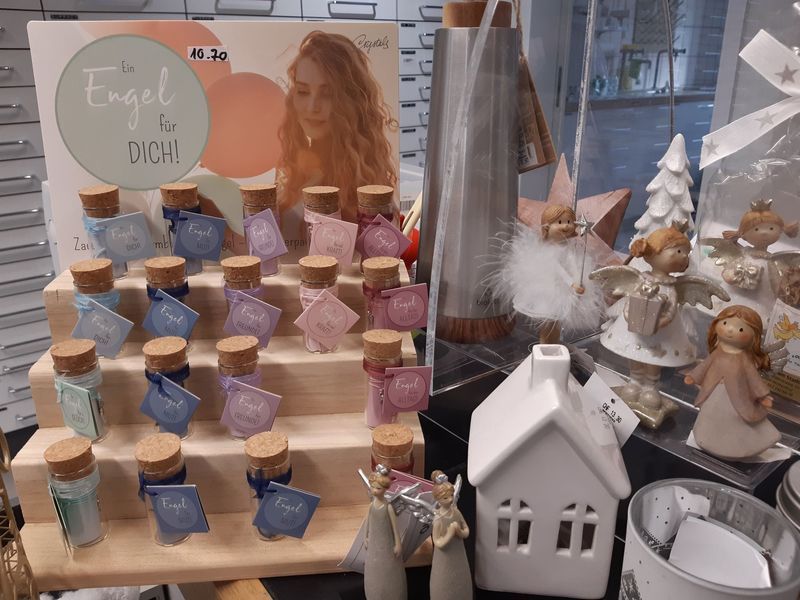 Ausstellung von kleinen Glasflaschen mit Korken, dekorativen Figuren und einem Schild in einem Geschäft.