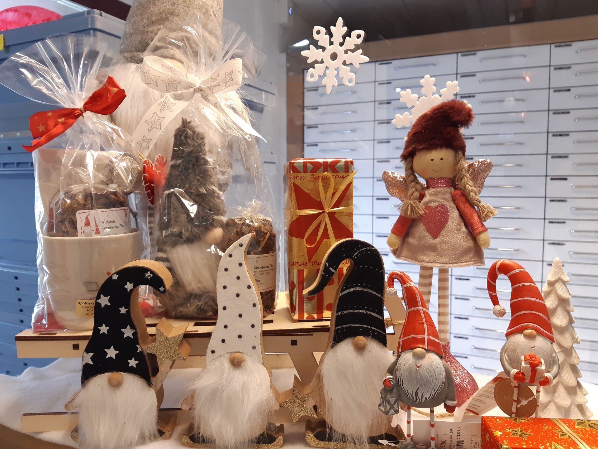 Weihnachtliche Schaufensterdekoration mit Wichteln, Geschenken und einem dekorativen Engel.