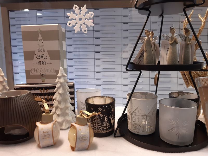 Weihnachtliche Schaufensterdekoration mit Kerzen, Engeln, Deko-Bäumen und einer Schneeflocke.