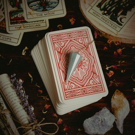 Tarot cards and crystals on a dark cloth, with a deck topped by a silver cone and scattered cards nearby