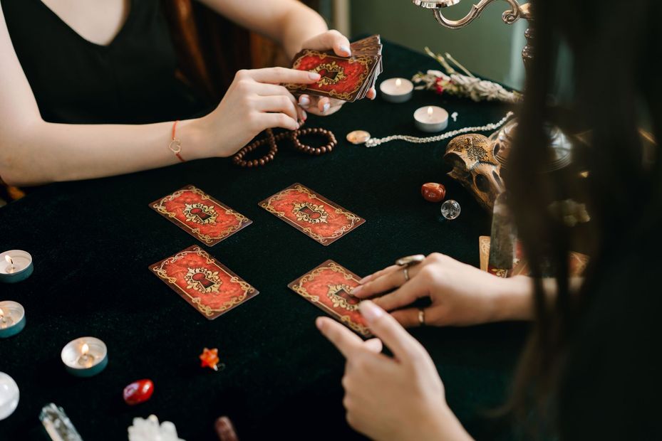 Hands arranging tarot cards and crystals on a black cloth during a reading