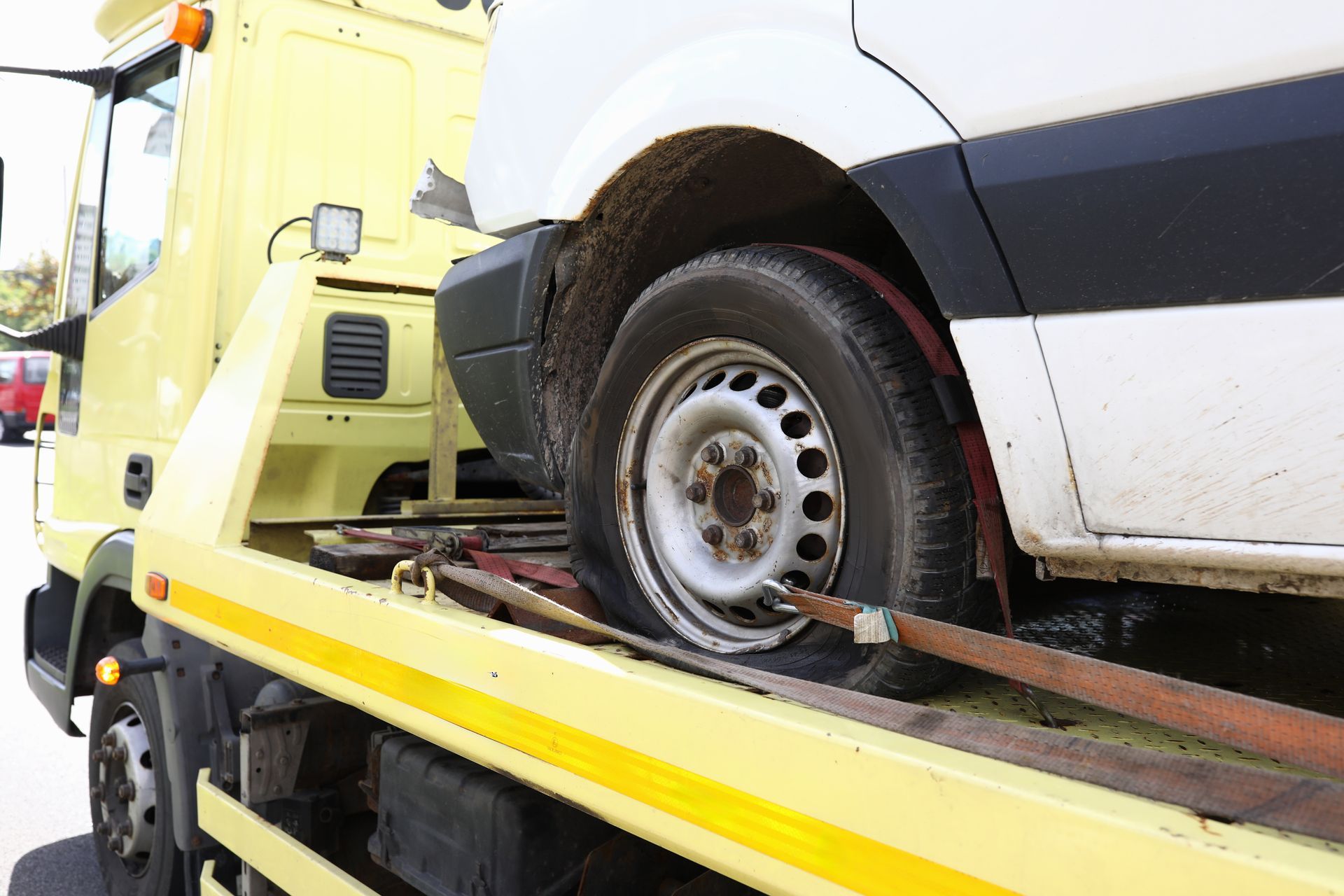 White van being towed on a yellow flatbed tow truck.