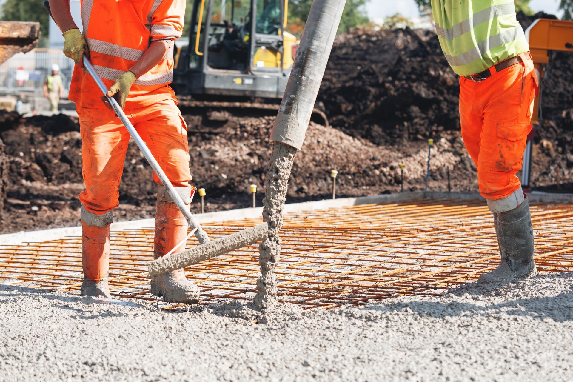 Concrete driveway contractor overseeing concrete pouring at a construction site with a pump. Concrete driveway contractor overseeing concrete pouring at a construction site with a pump.