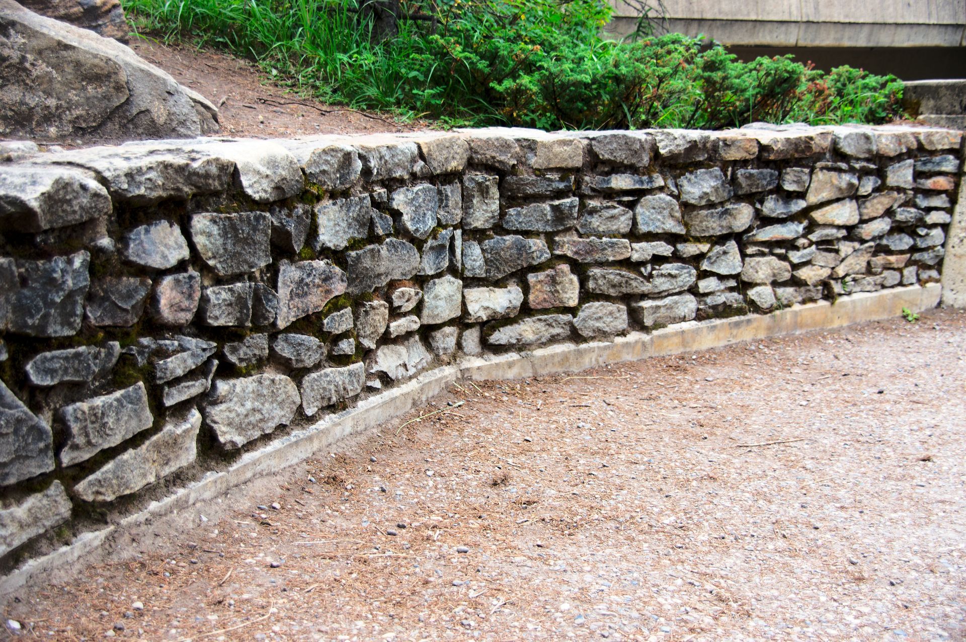 Stone Retaining Wall Bordering a Gravel Path and Greenery — Tucker, GA — A-1 Driveway Replacement Company