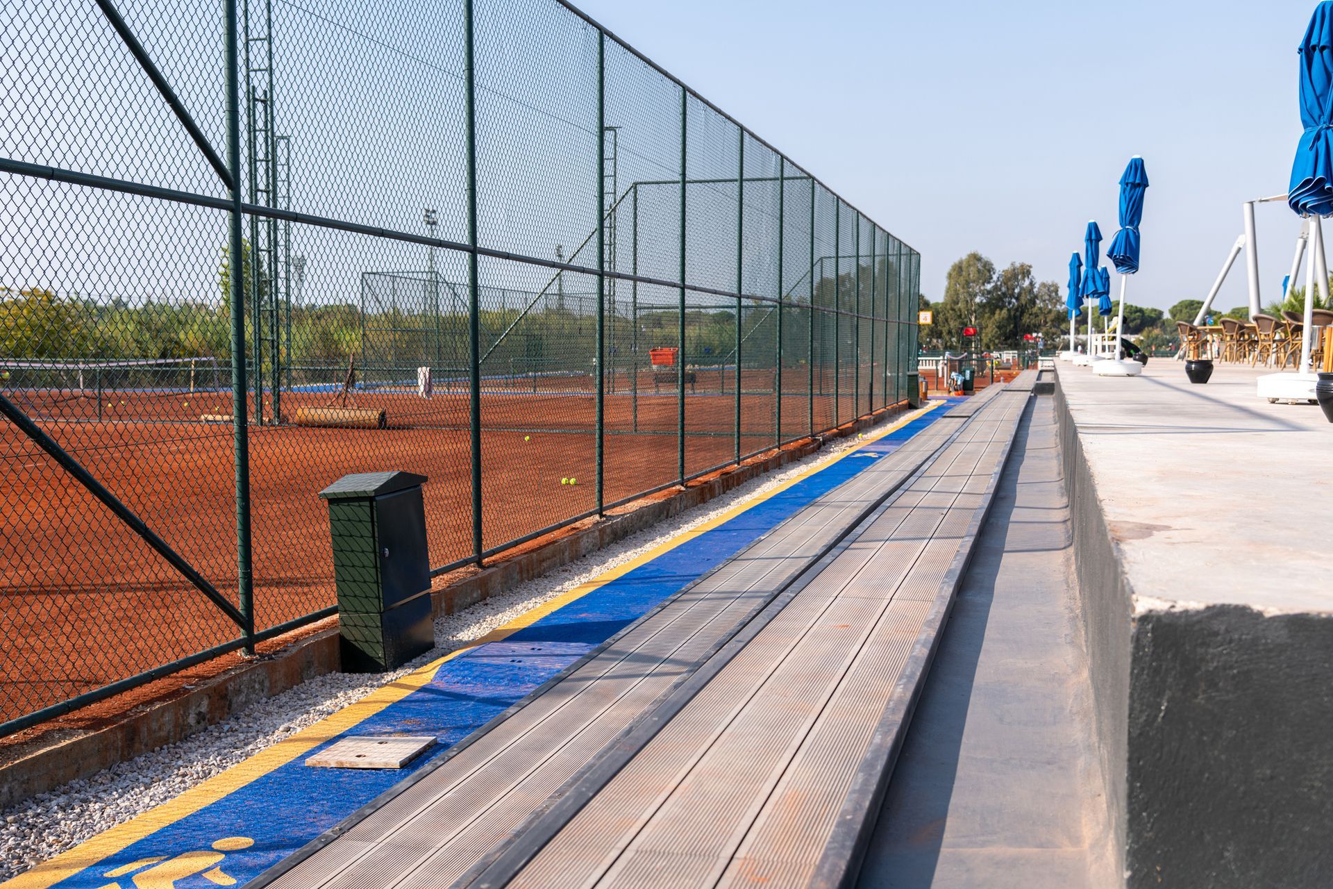 Fence-Lined Walkway Beside a Tennis Court with Blue and Wooden Features — Tucker, GA — A-1 Driveway Replacement Company