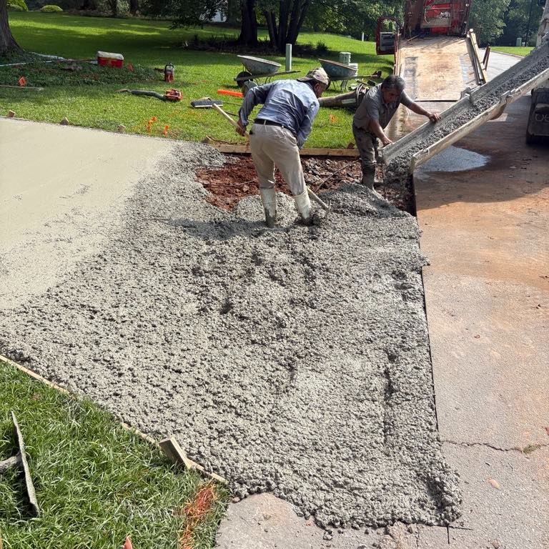 Workers spreading wet concrete on a driveway with shovels, a truck pouring concrete. Workers spreading wet concrete on a driveway with shovels, a truck pouring concrete.