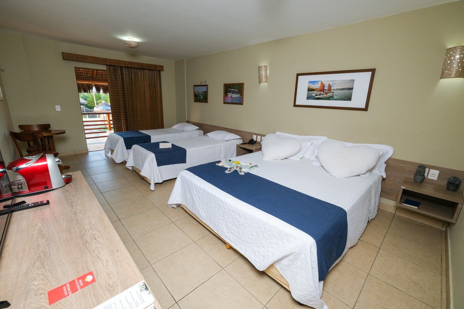 Um quarto de hotel com três camas e uma porta de correr.