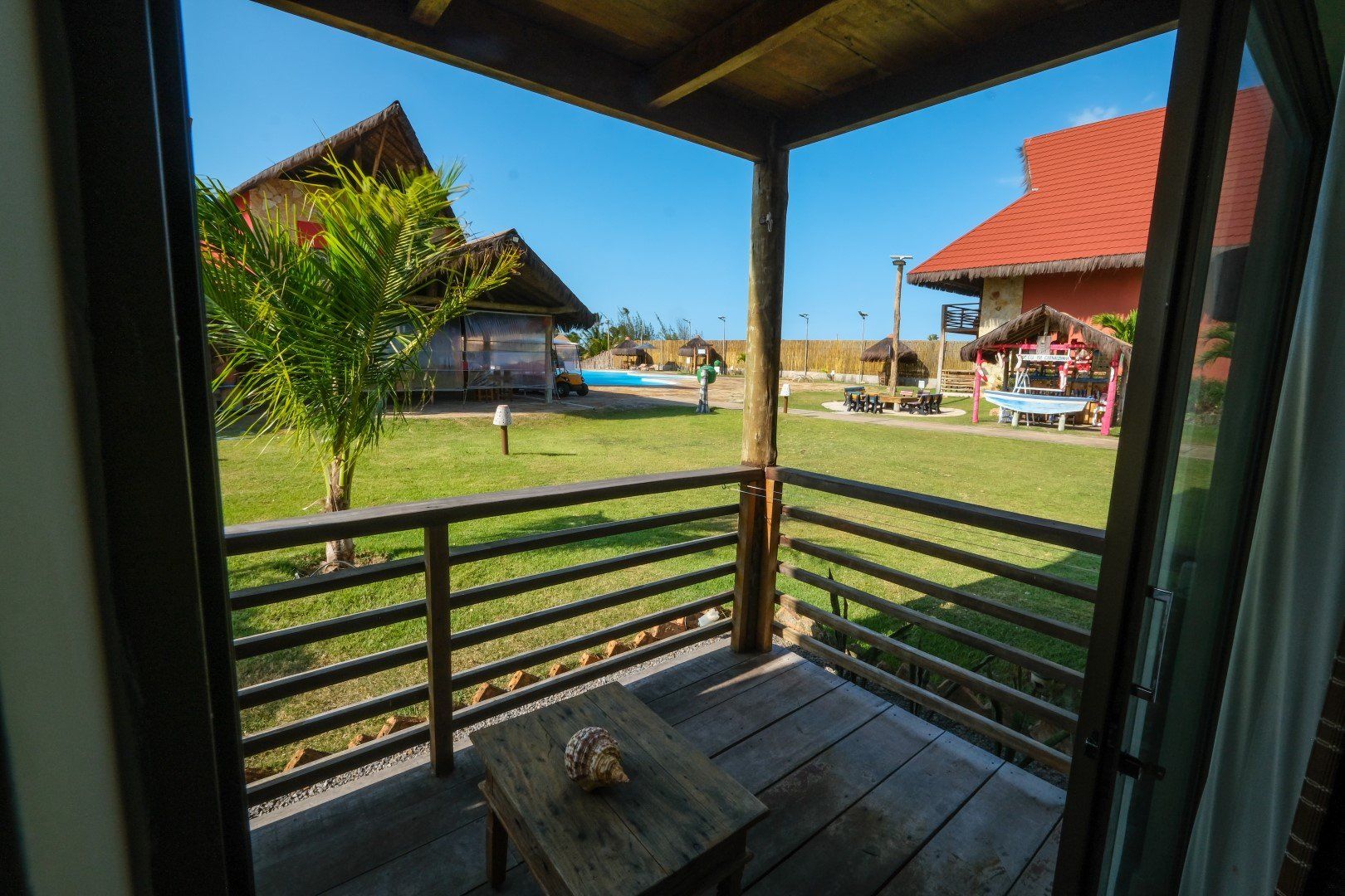 Uma varanda com mesa e cadeiras com vista para um campo verdejante.