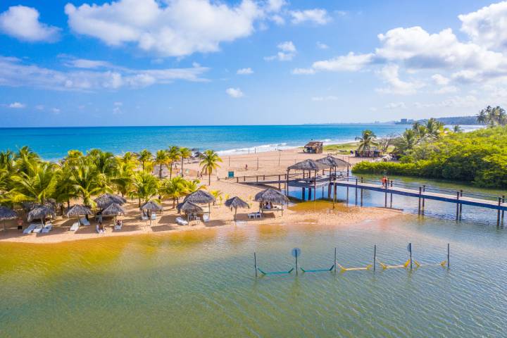 Uma vista aérea de uma praia com guarda-sóis e um cais.