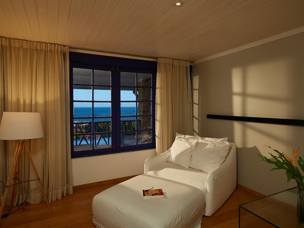 Uma sala de estar com uma grande janela e uma cadeira branca