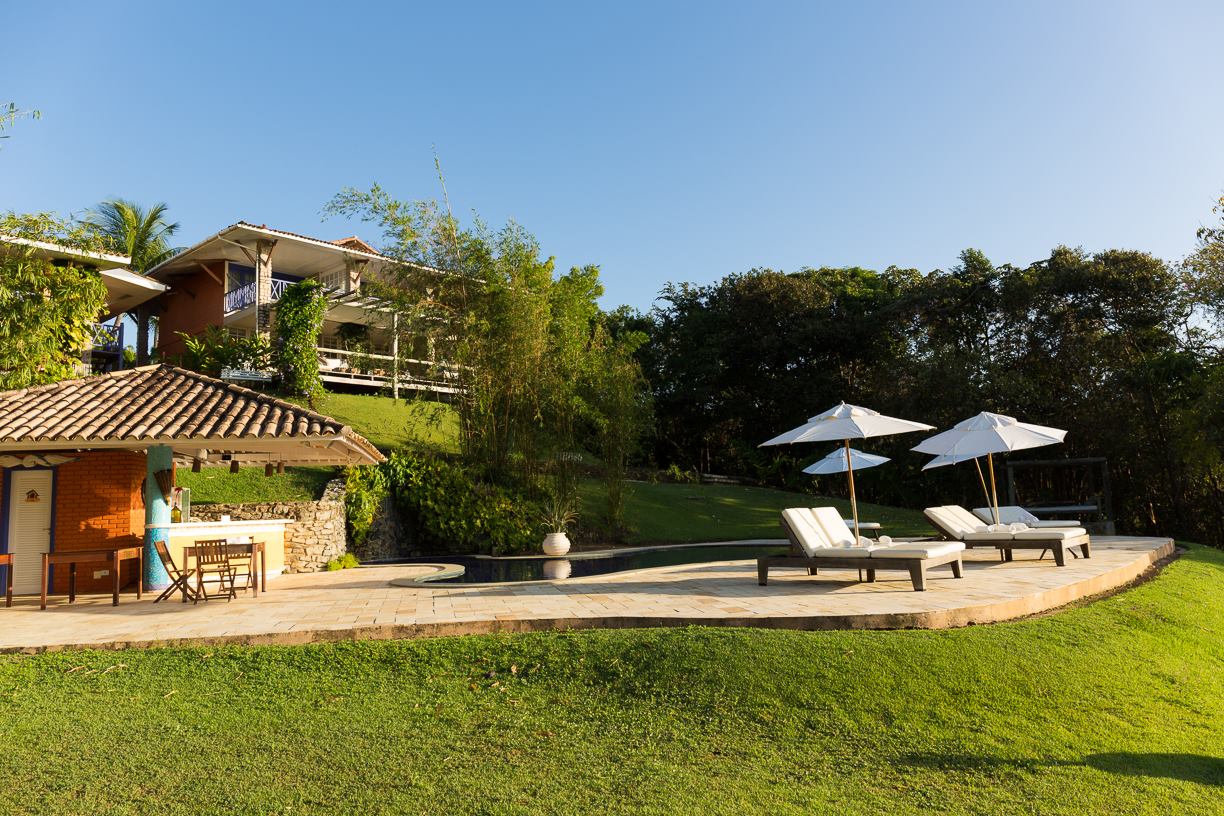 Um gramado com cadeiras e guarda-sóis em frente a uma casa