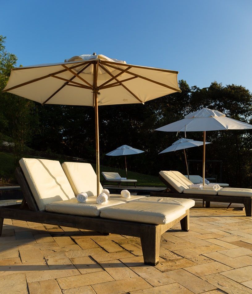 Um pátio com espreguiçadeiras e guarda-sóis em um dia ensolarado