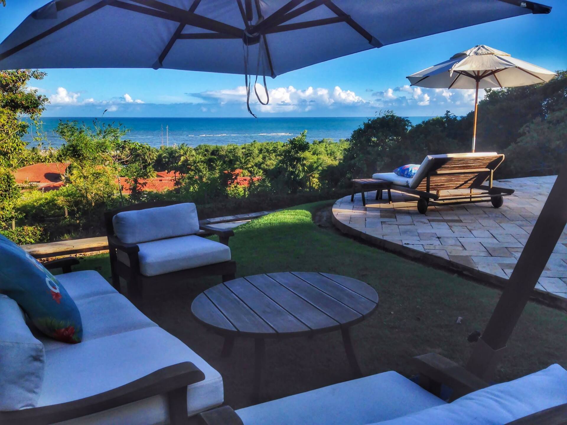 Um pátio com cadeiras e guarda-sóis com vista para o oceano