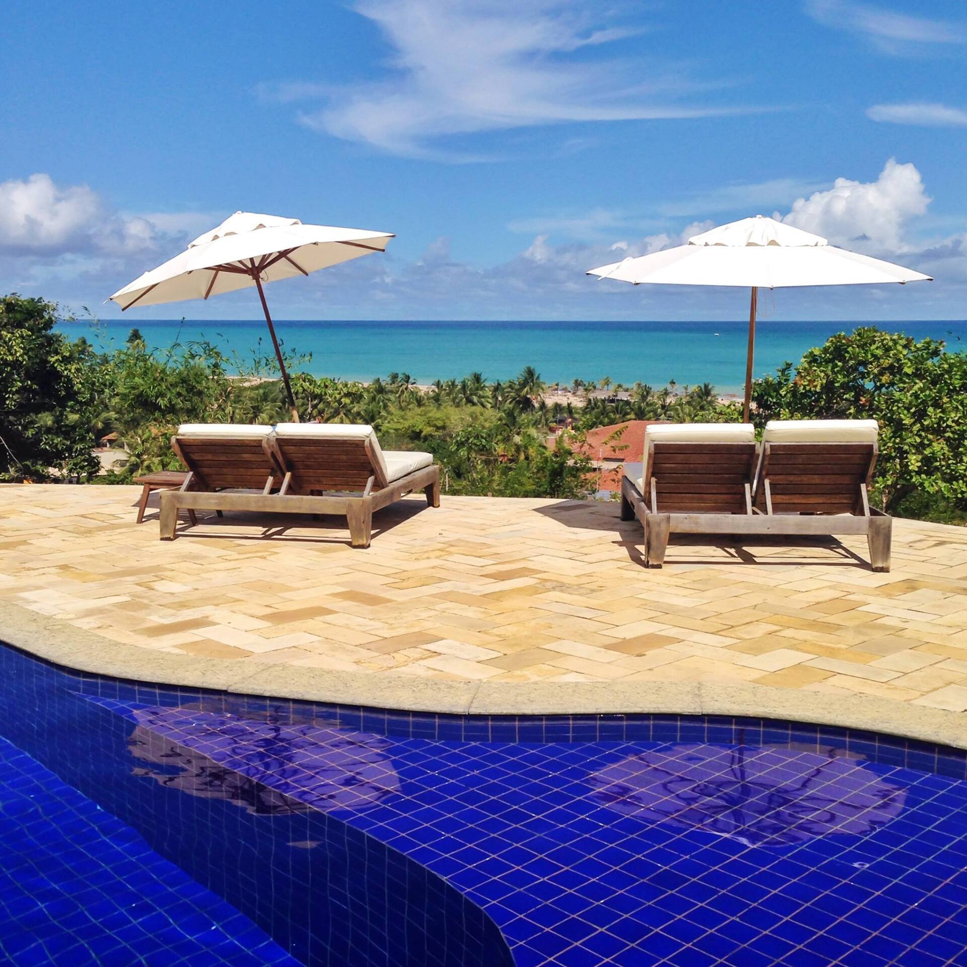 Uma piscina com duas espreguiçadeiras e dois guarda-sóis