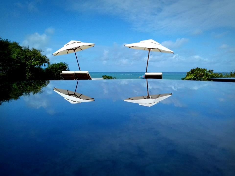 Dois guarda-chuvas são refletidos em uma piscina