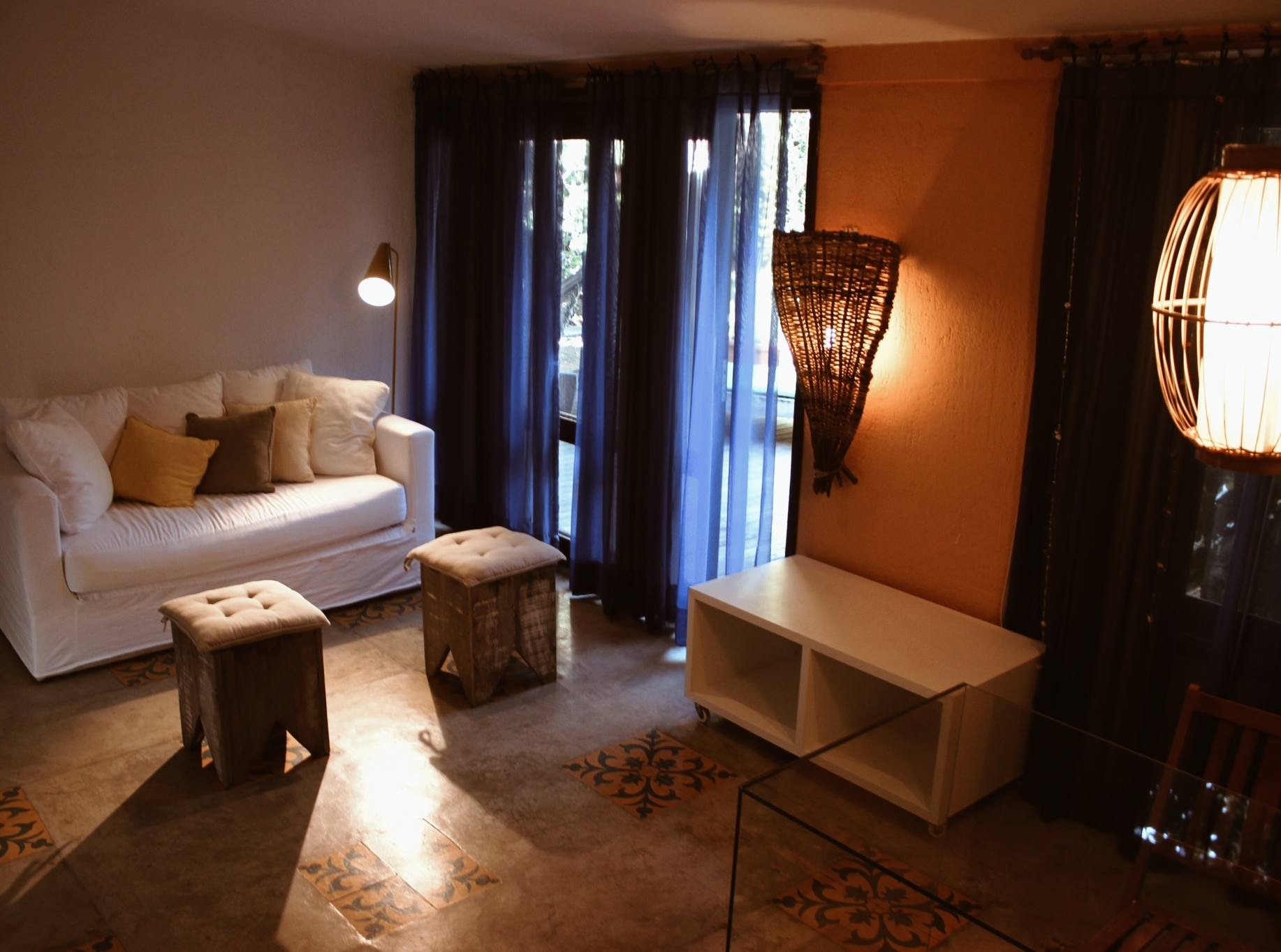 Uma sala de estar com um sofá, pufes e uma mesa de centro