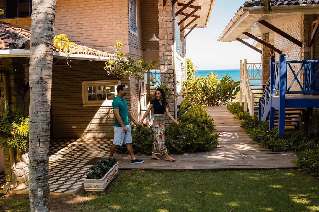 Um homem e uma mulher estão caminhando em frente a uma casa de mãos dadas.