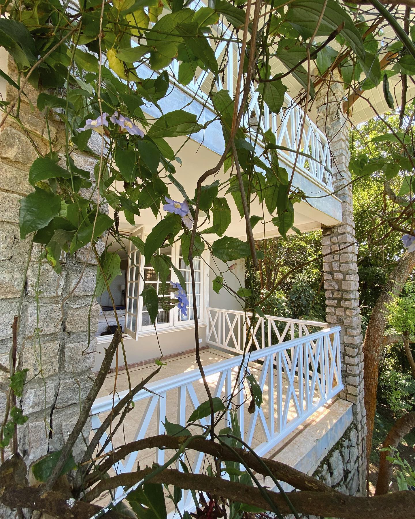 Uma casa com uma varanda e uma árvore na frente.