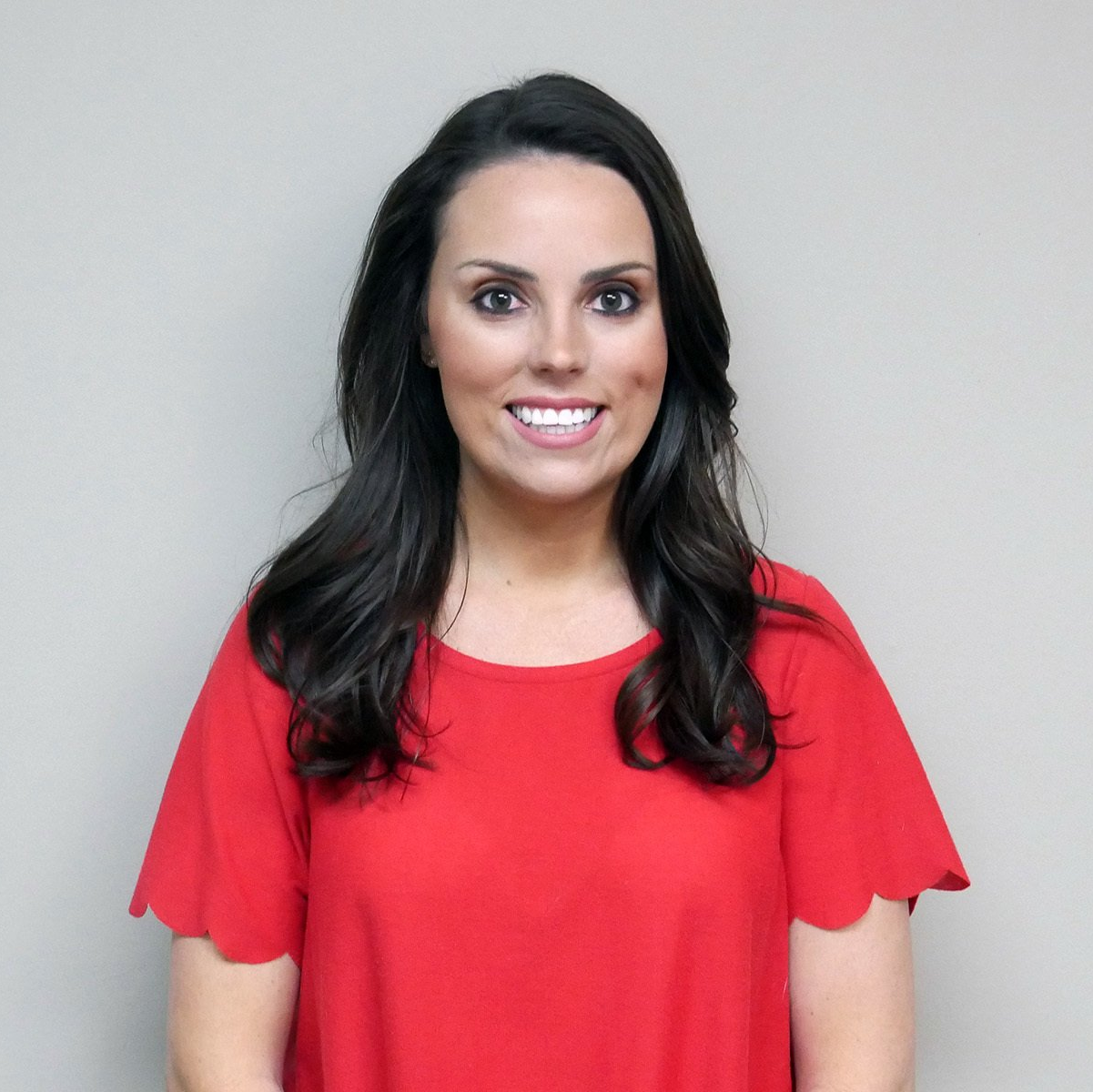 A woman in a red shirt is smiling for the camera