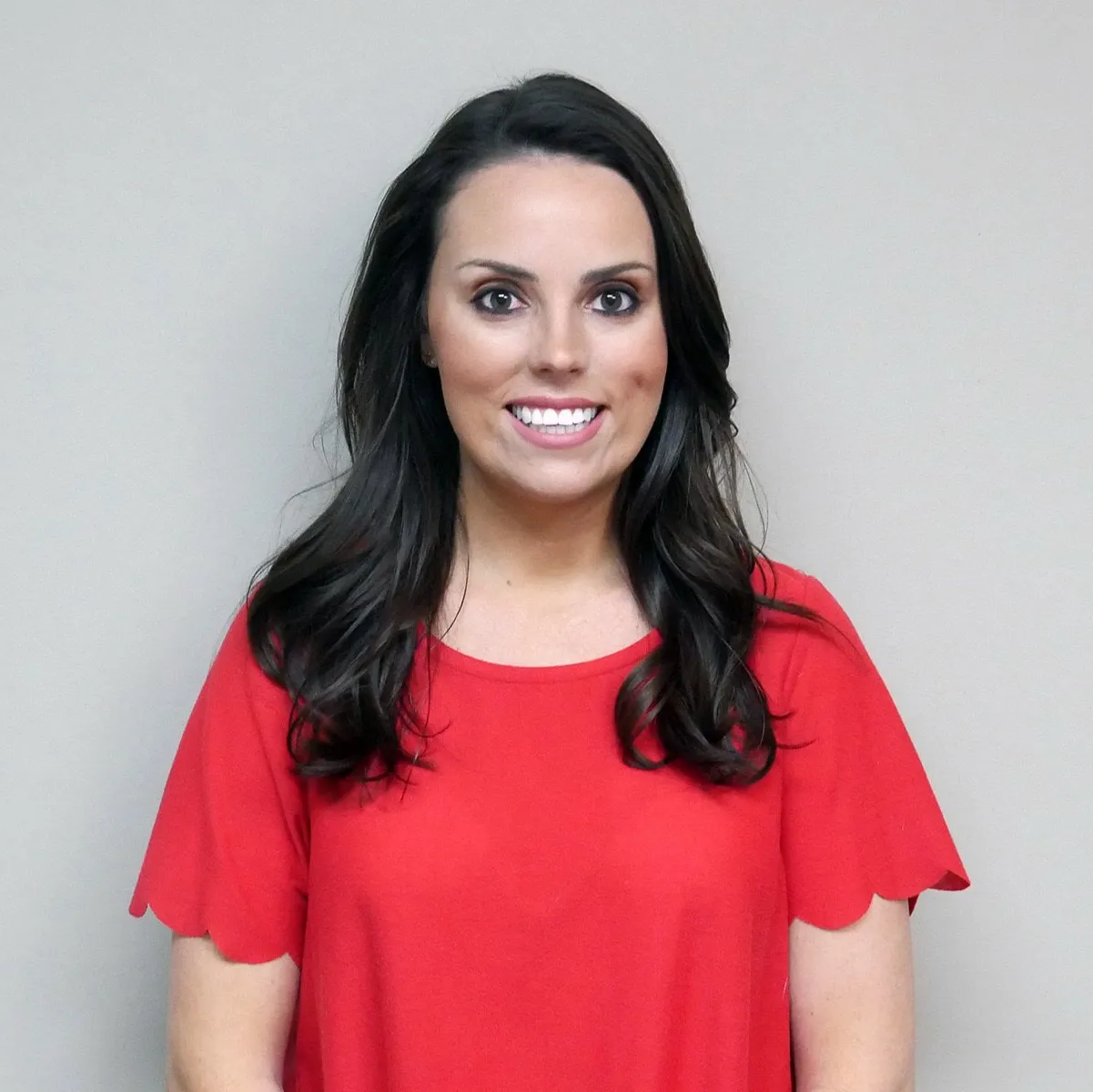 A woman in a red shirt is smiling for the camera