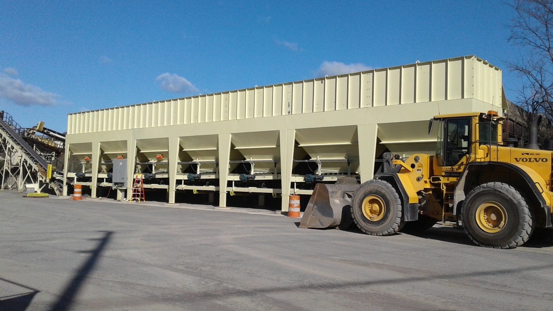 A yellow volvo wheel loader is parked in front of a building.